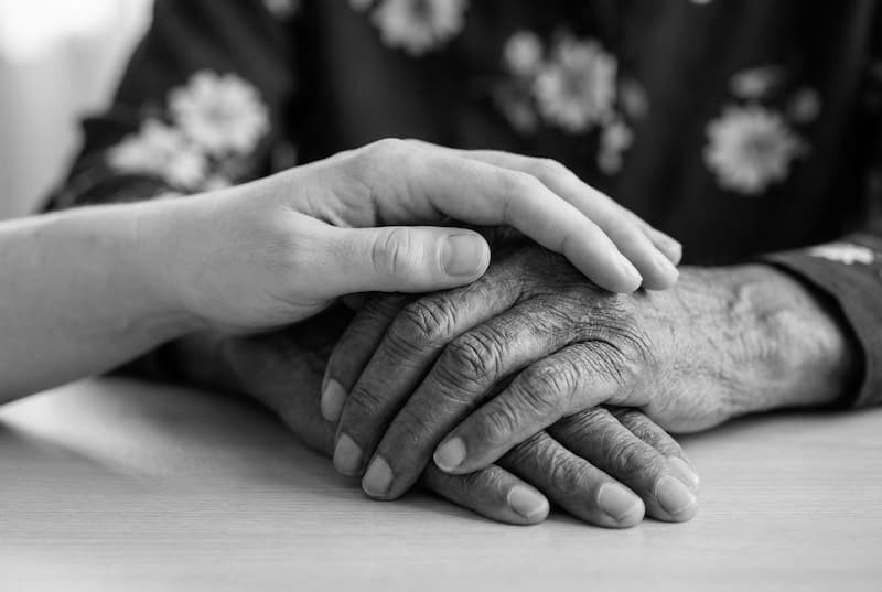 Massage de répit : une main posée avec douceur sur les mains d’une personne âgée