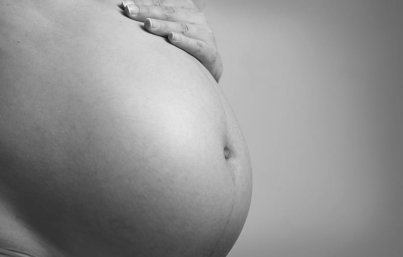 Massage pour femme enceinte : main posée sur le ventre arrondi d’une future maman
